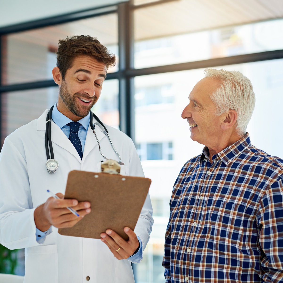 Médico profesional sonriendo mientras comparte buenos resultados con su paciente en consultorio, transmitiendo confianza y profesionalismo